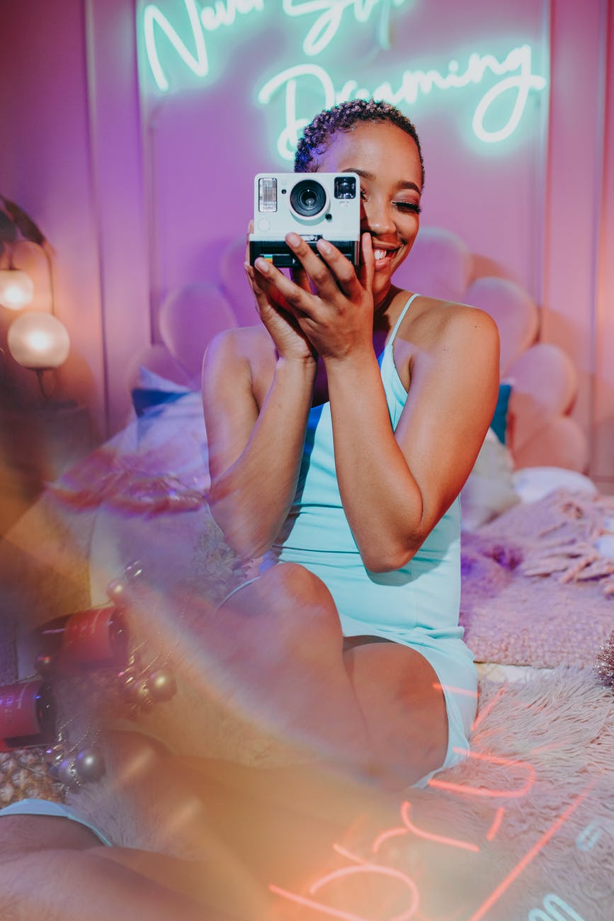 woman in blue tank top holding iphone