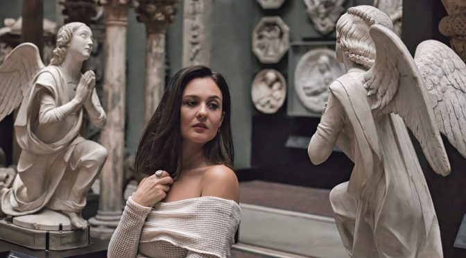 a woman standing between angel statues